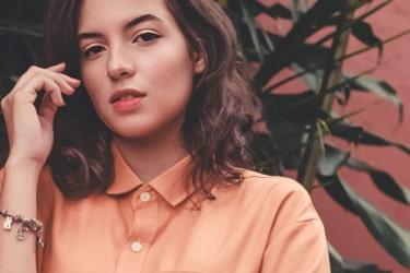 girl wearing kind of orange shirt and looking at you